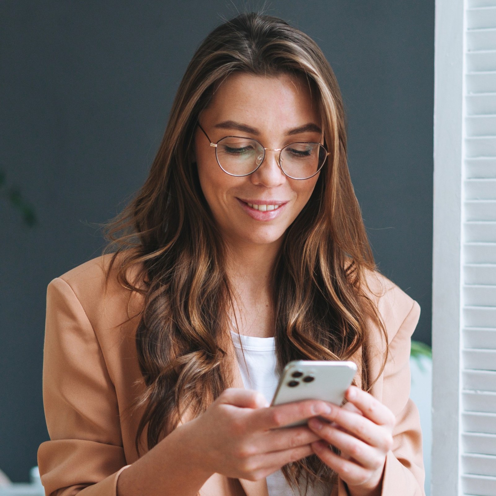 Woman with long brown hair wearing thin-rimmed glasses